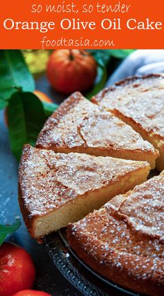 an orange olive oil cake with powdered sugar on top and apples in the background