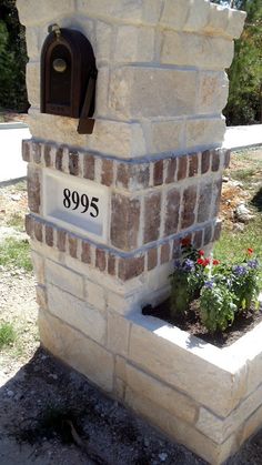 a brick mailbox with flowers growing out of it