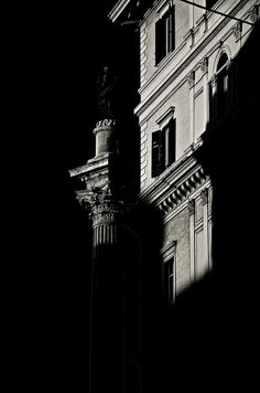 a black and white photo of an old building with a clock on it's side