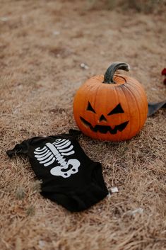 a halloween pumpkin with a skeleton t - shirt laying on the ground next to it