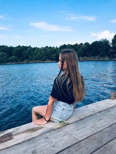 a woman sitting on the end of a dock