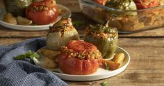 some stuffed peppers are on a plate with other food items in the bowl behind them