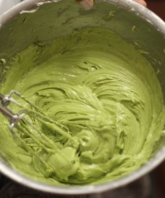 a person mixing green food in a bowl