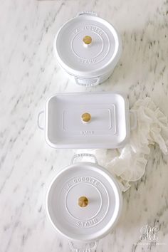 three white dishes sitting on top of a marble counter next to each other with gold knobs