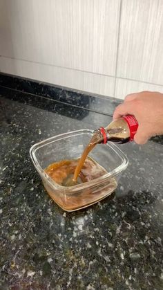 someone pouring sauce into a bowl on top of a counter