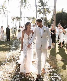 a man and woman walking down a path in front of palm trees with confetti on the ground