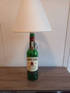 a green bottle sitting on top of a wooden table next to a white lampshade