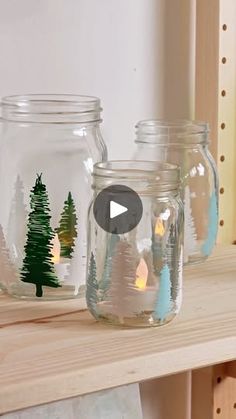 three glass jars with christmas trees in them sitting on a shelf next to a window