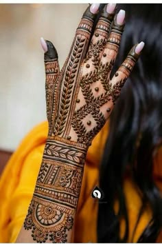 a woman's hand with henna tattoos on her arm and hands, showing the intricate