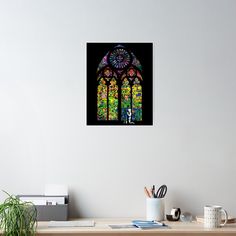 a colorful stained glass window on the wall above a desk with a pen and pencil holder