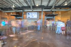 a group of people standing around in a room with a large screen on the wall