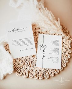 the wedding stationery is laid out on top of a doily with a feather