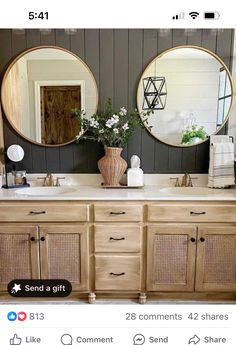 a bathroom with two round mirrors on the wall and wooden cabinets in front of it