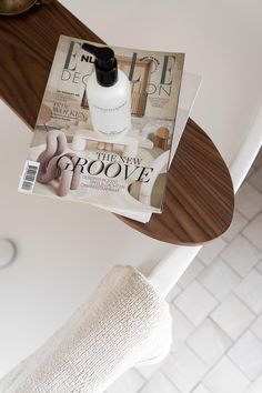 a magazine sitting on top of a wooden table next to a white towel and toilet