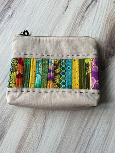 a small zippered pouch is decorated with multicolored fabric and stitching details