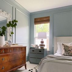 a bedroom with a bed, dresser and mirror in the corner next to a window