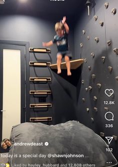 a young child climbing up the side of a wall in a room with rocks on it