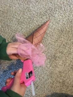 a person is holding a pink object with a cone on it's head and an ice cream cone in the other hand