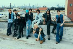 a group of young men sitting on top of a roof next to each other in front of a city skyline