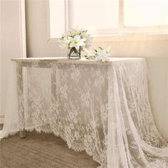 the table is covered with white lace and flowers