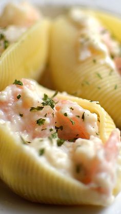 a white plate topped with pasta shells covered in sauce and garnished with parsley