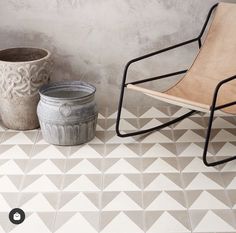 a chair sitting next to a potted plant on top of a tiled floor