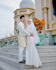 a man and woman standing next to each other on some steps