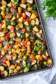 a pan filled with potatoes, broccoli and carrots on top of a table