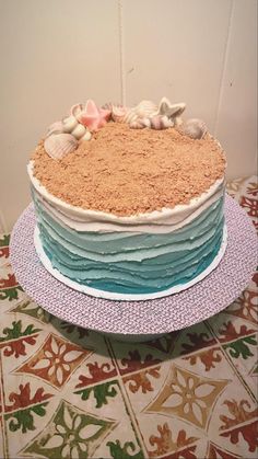 there is a cake that has shells on it and sand in the top layer, along with seashells