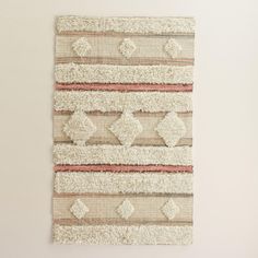 a wall hanging made out of rugs on a white wall next to a window