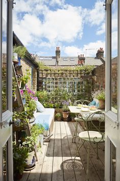 an open door leading to a small patio with potted plants on the table and chairs