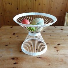 a white wire fruit stand on top of a wooden table