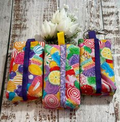 four colorful bags are lined up on a wooden surface with flowers in the middle and one is empty