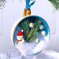 a christmas ornament hanging from a tree with snow and ornaments in the background