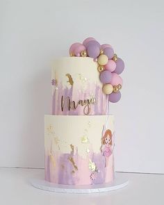 a three tiered cake with purple and gold decorations