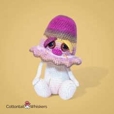 a crocheted stuffed animal wearing a pink hat and holding a small white object