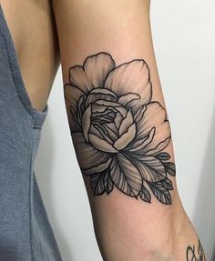 a black and white flower tattoo on the right arm, with an inscription below it