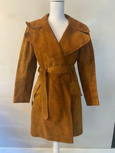 Channel the effortless style of the 1970s with this stunning vintage suede trench coat. This brown belted jacket features wide lapels and a rich, textured finish, offering a sophisticated yet timeless look. Perfect for both casual and formal occasions, this trench coat is a rare find that brings retro charm to any wardrobe. Its impeccable craftsmanship and classic design make it an essential piece for vintage fashion lovers. MEASUREMENTS:  Bust: 40" Waist: 38" CONDITION:  Excellent- Small discoloration in interior armpit. 🚦KEEP IN MIND -Please read the evaluation report of this vintage garment CAREFULLY 👀 before making the order (see referenced photos if applicable) Although we evaluate the item thoroughly and carefully, 1 or 2 imperfections may be missed and not stated in the descriptio Vintage Belted Outerwear For Work, Retro Belted Outerwear For Work, Retro Belted Outerwear For Fall, Retro Belted Fall Outerwear, Fall Suede Belted Outerwear, Fitted Vintage Outerwear With Belt Loops, Fitted Vintage Belted Outerwear, Vintage Belted Workwear Outerwear, Vintage Suede Outerwear For Fall