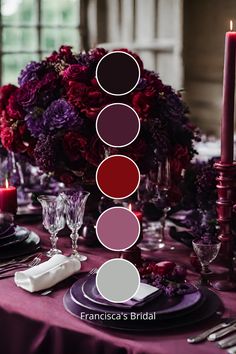 the table is set with purple and red flowers, silverware, candles, and napkins