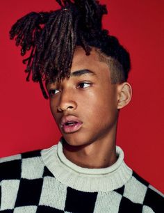 a young man with dreadlocks on his head wearing a black and white sweater