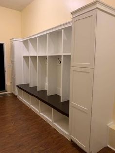 an empty room with white cabinets and black counter tops in the center, along with wooden floors