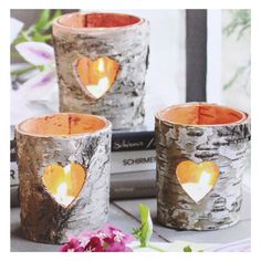 two birch trees with hearts cut out of them, sitting on a table next to flowers