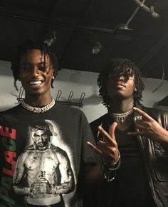 two young men standing next to each other in front of a rack with jewelry on it