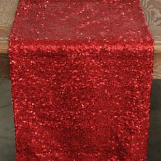 a red sequin table runner sitting on top of a wooden bench