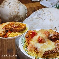 two bowls filled with spaghetti and meat covered in cheese