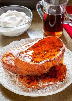 two pieces of bread sit on a plate next to a cup of tea and whipped cream