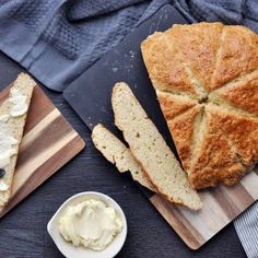 sliced loaf of bread with butter and blueberries on cutting board next to bowl of whipped cream