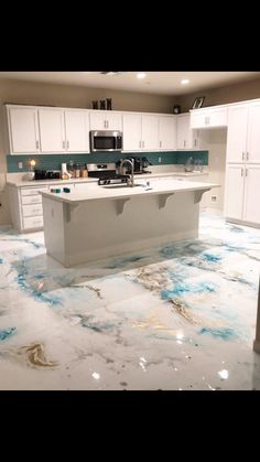 a kitchen with marble flooring and white cabinets in the background, there is an island that has blue paint on it