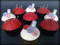 cupcakes decorated with red and white frosting, topped with buttons and pins