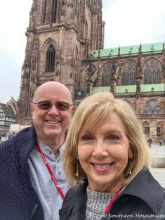 a man and woman standing in front of a large building with a clock on it